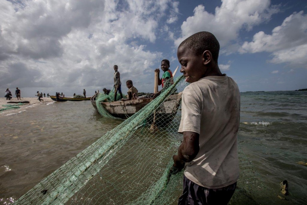 A young boy helps haul in a net on Praia Nova, Angoche District, Mozambique (© JamesMorgan)